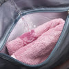A pink towel is being rinsed with water inside a gray travel duffle bag.