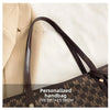 A close-up view of a brown faux leather handbag with a monogram pattern and a dark brown strap resting on a light background.