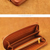 A brown genuine leather zipper wallet is shown open on a tan background.