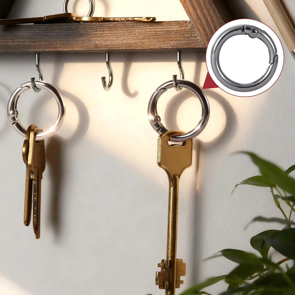 A set of sturdy metal key ring clips with spring-loaded fasteners hanging on a wooden rack.