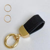 Goldfarbener Leder-Schafsfell-Auto-Schlüsselanhänger mit schwarzem Band und runden Ringen.