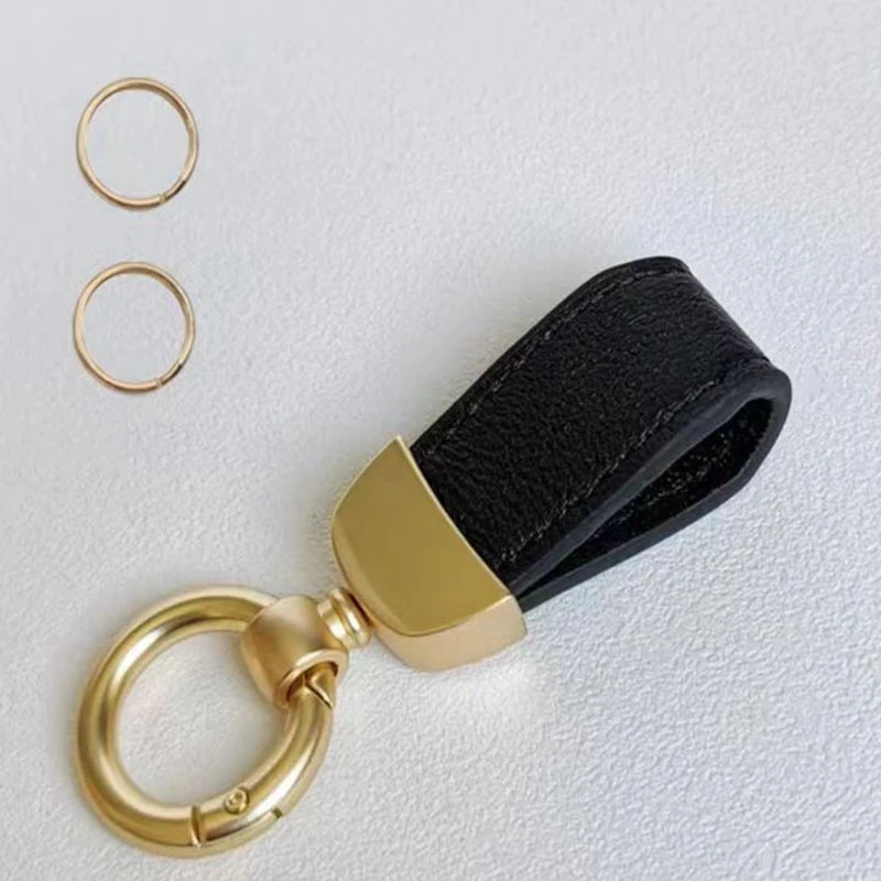 Goldfarbener Leder-Schafsfell-Auto-Schlüsselanhänger mit schwarzem Band und runden Ringen.