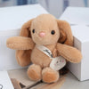 A fluffy light brown plush rabbit toy with pink accents sitting next to a white tag.