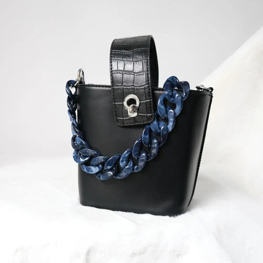 Black acrylic resin detachable bag chain strap attached to a black leather handbag