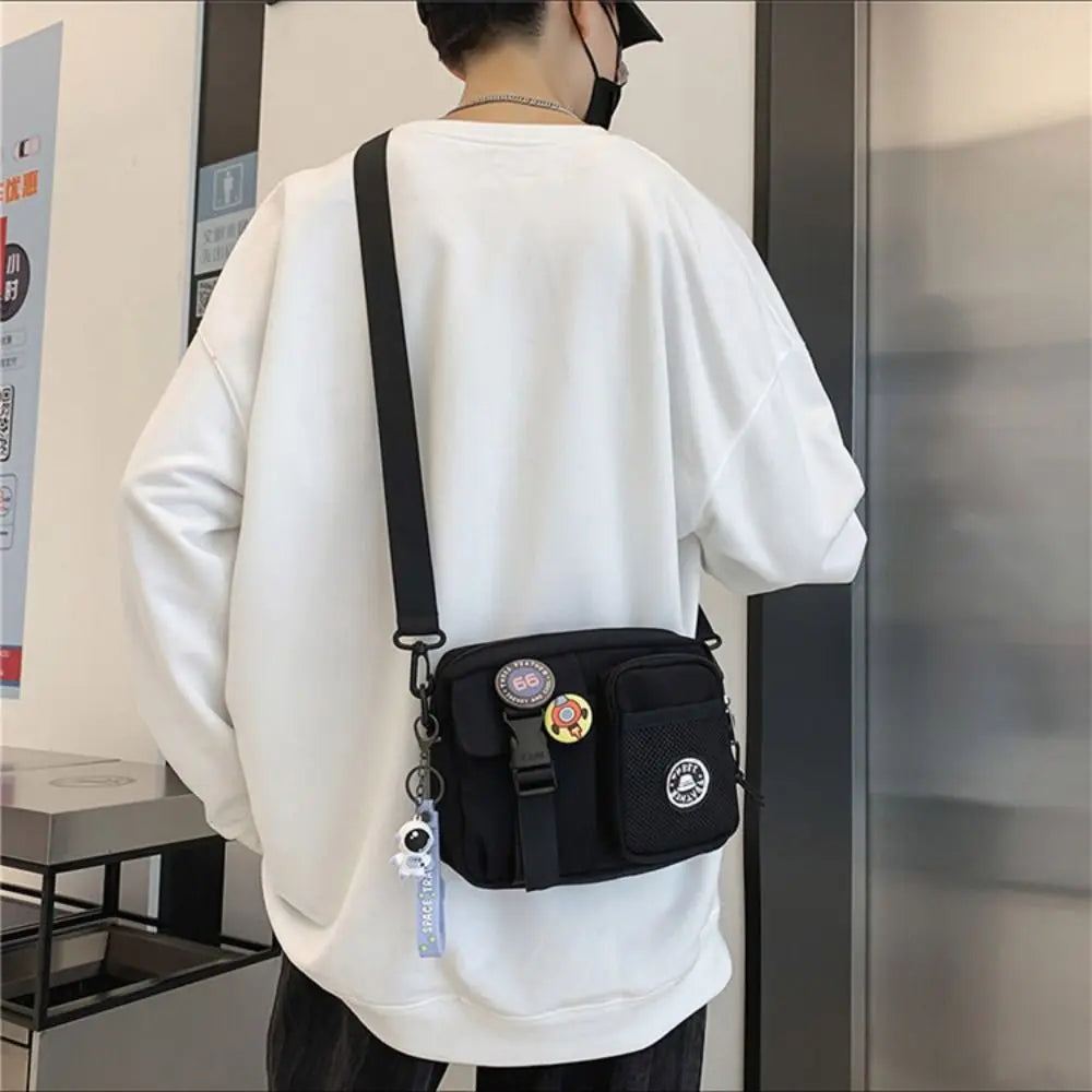 A person wearing a white sweatshirt is shown from the back, holding a black canvas shoulder bag with various charms.
