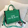 A bright green canvas tote bag with black trim is displayed on a white textured surface.
