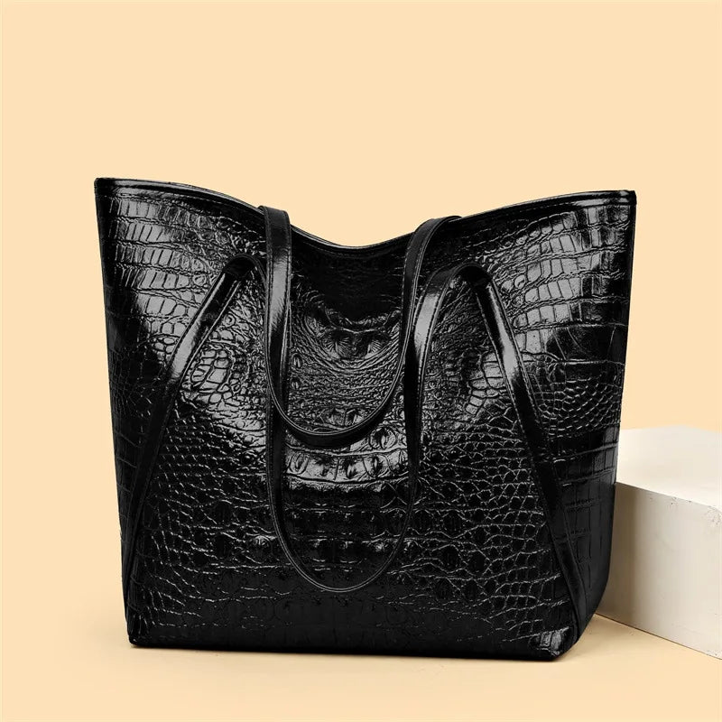 A black crocodile print tote bag is displayed on a light background.