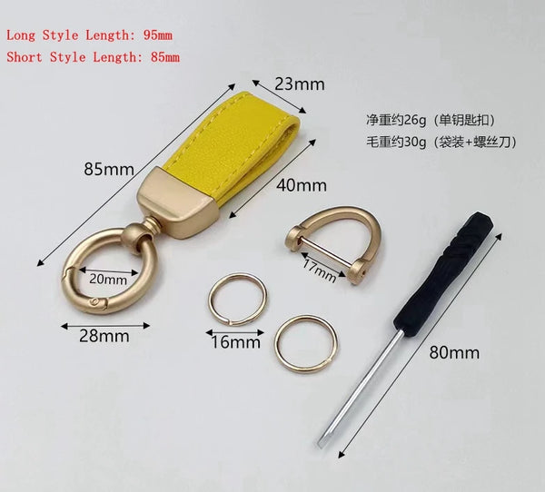 A yellow leather key chain with a gold-colored clasp and various rings and a long metal rod shown on a white background.