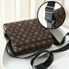 A brown patterned men's casual crossbody bag with a black strap is shown on a white surface.