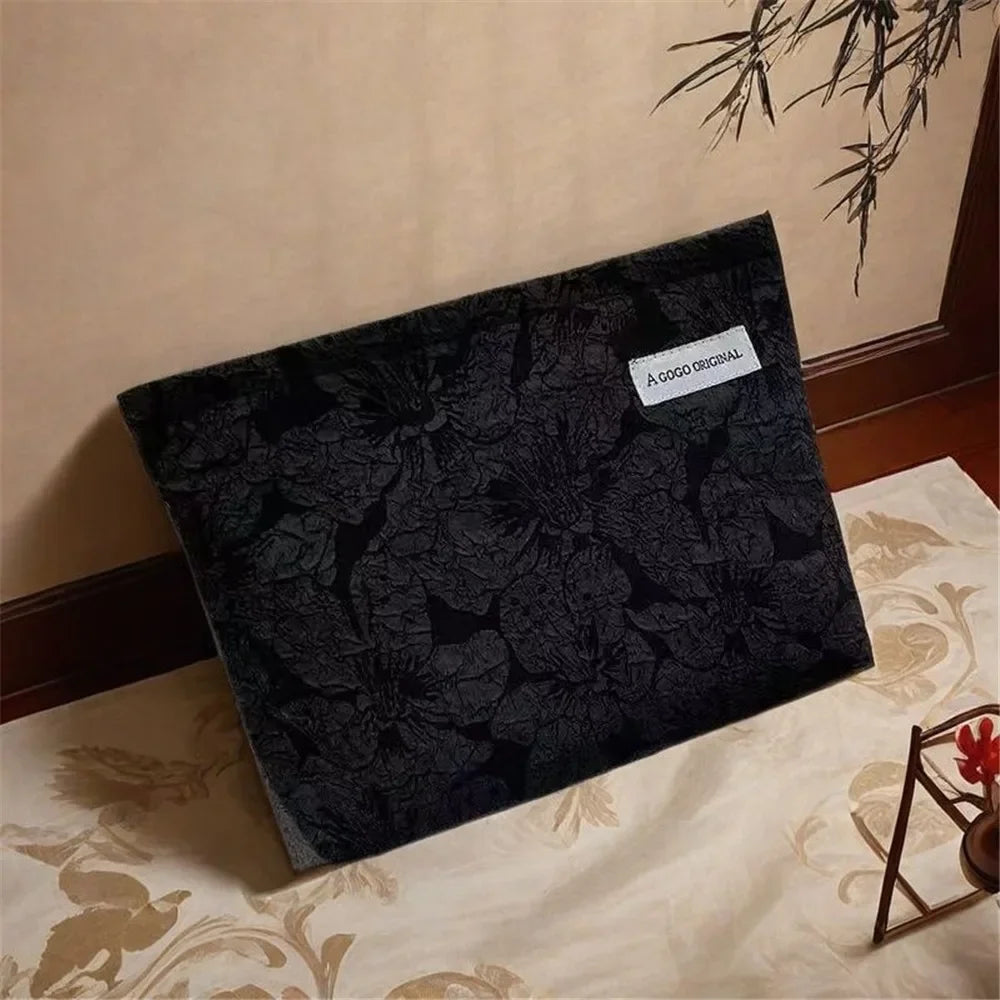 Bolsa de cremallera de lona gris oscura para almacenar electrónica sobre una superficie de tela clara.