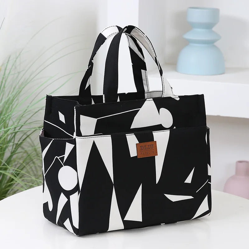 A black and white geometric pattern cloth tote bag is displayed on a white surface.