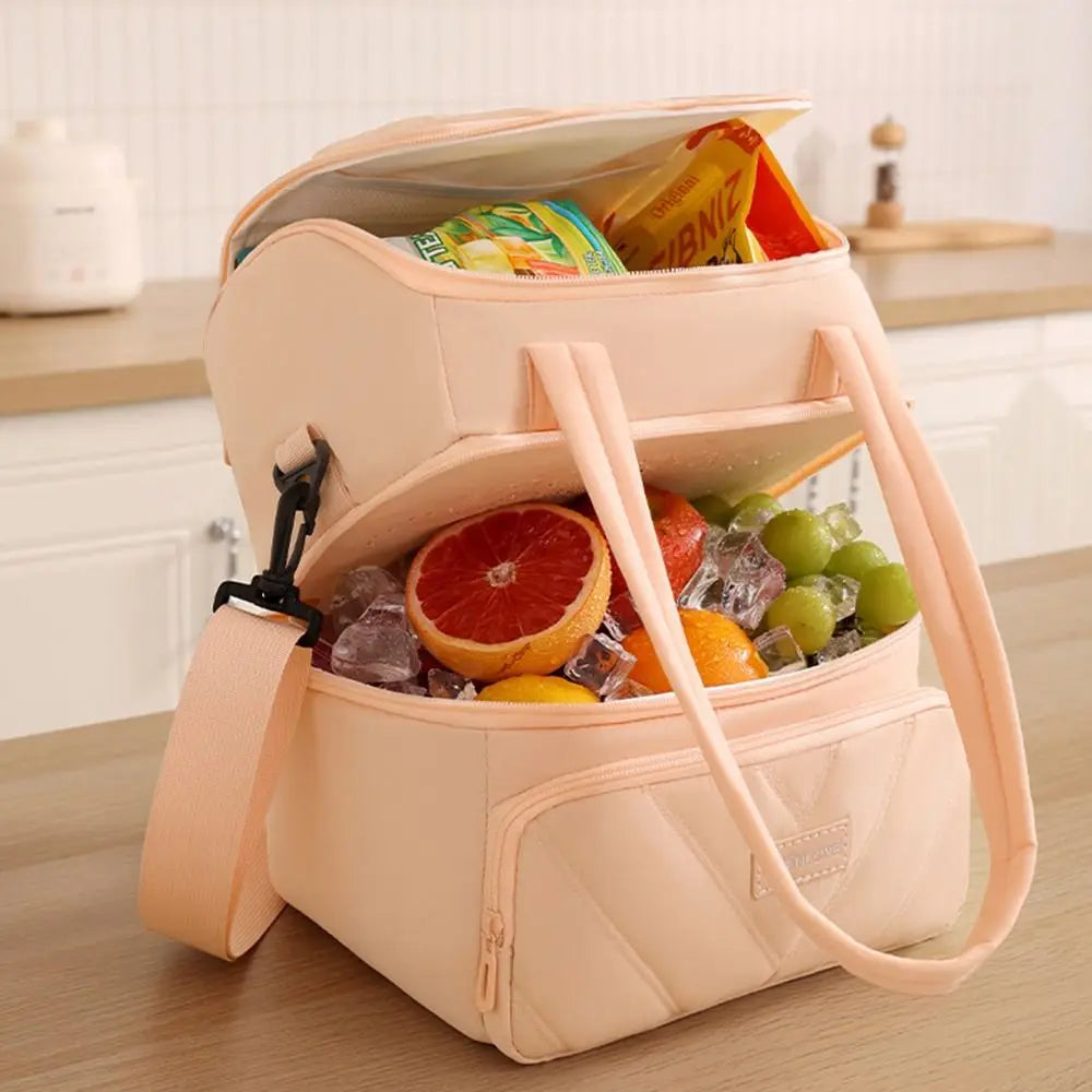 Una bolsa térmica reutilizable de color rosa claro llena de hielo y snacks coloridos.