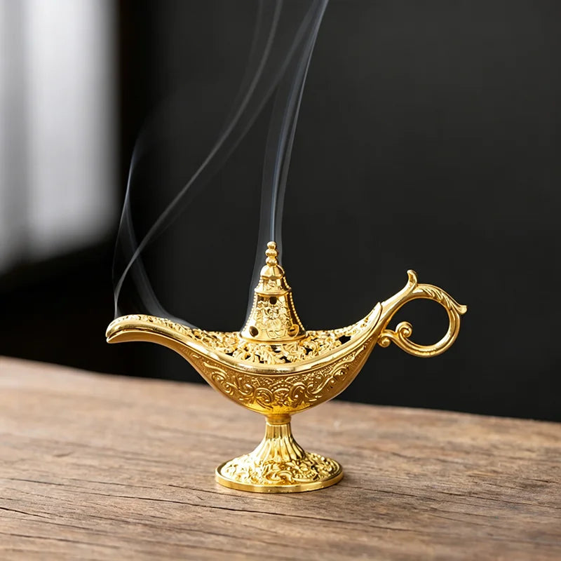 A golden antique metal incense burner with a spout and handle rests on a wooden surface.