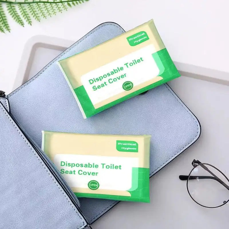 A green and white disposable toilet seat cover is shown resting on a light blue folder or notebook.