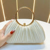 A hand holds an elegant satin pleated evening clutch bag with a gold rim against a light background.