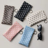 A collection of five polka dot eyeglass pouches in various colors, including brown, black, white, and pink, with metal keycha