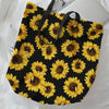 Black canvas tote bag featuring a repeating pattern of yellow sunflowers.