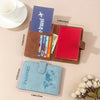 A brown leather passport wallet with a red card holder and a blue passport sleeve, next to a light pink surface.