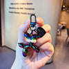 A hand holds a shiny, iridescent balloon dog keychain charm with a metal clasp.