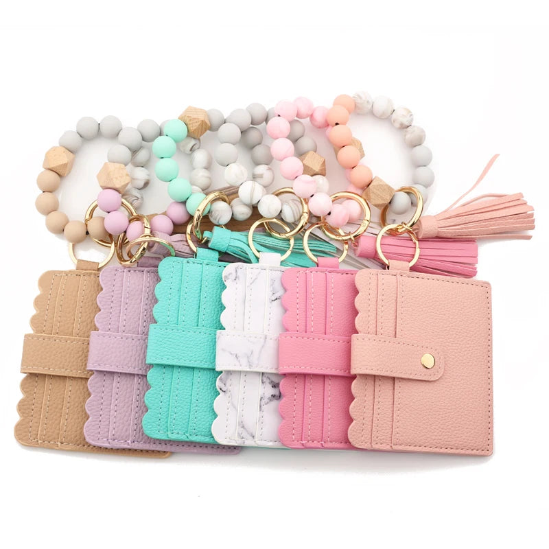 A collection of silicone bead bracelets and a leather card holder in various pastel colors.
