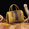 A luxury crocodile pattern leather crossbody tote bag in yellow and brown tones resting on a wooden surface.