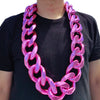 A man wearing a chunky pink acrylic Cuban link necklace around his neck.