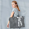 A woman wearing a light gray top holds a dark gray vintage PU leather laptop tote bag with a patterned scarf.