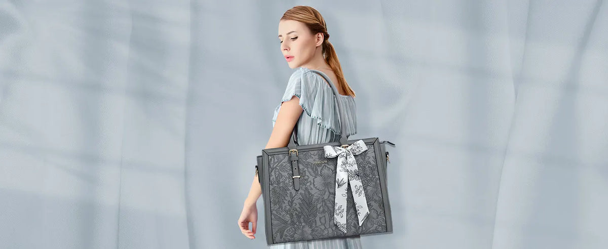 A woman wearing a light gray top holds a dark gray vintage PU leather laptop tote bag with a patterned scarf.