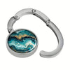 Silver portable bag hook with a round marble pattern charm featuring blue and green swirls.
