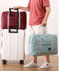 Une personne tient une valise à roulettes blanche et un sac de sport bleu clair.