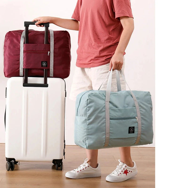 A person is holding a white rolling suitcase and a light blue duffle bag.