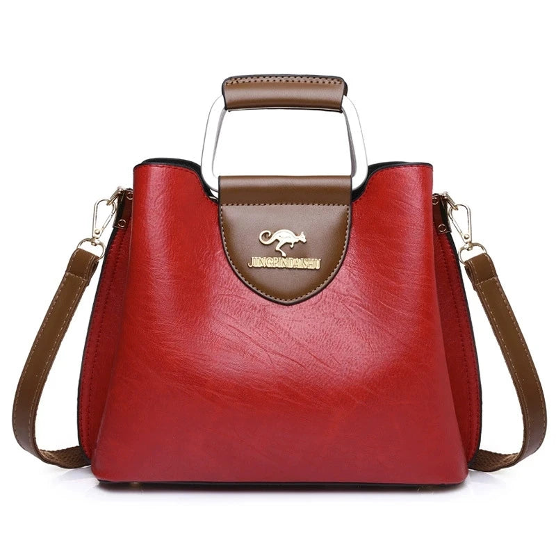Sac bandoulière vintage en cuir rouge profond avec poches, garniture marron et poignée argentée.