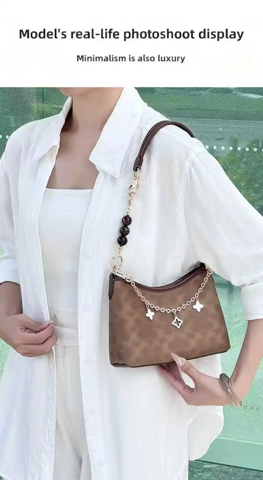 A model wears a white shirt over a white top and holds a brown leather crossbody bag with a gold chain detail.