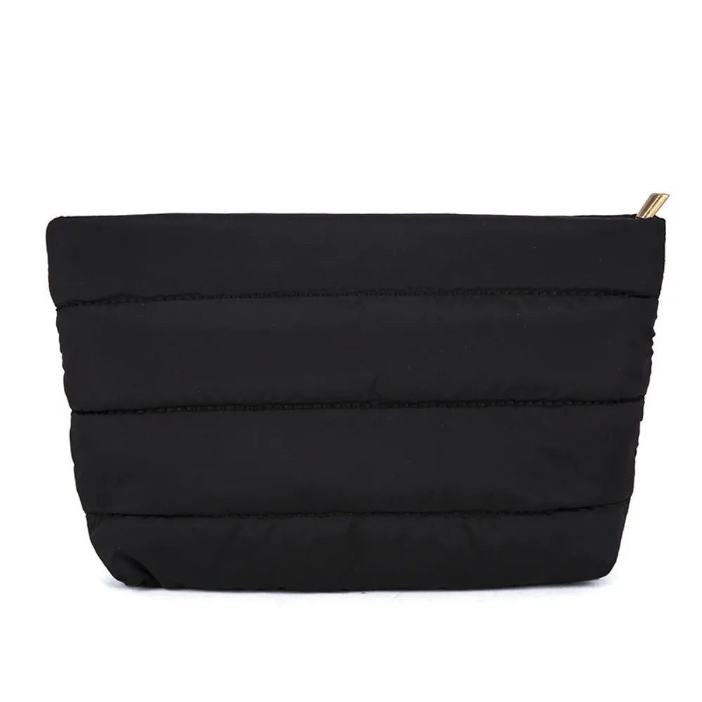 Black quilted cosmetic travel bag with a gold zipper pull.