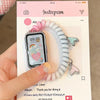 A close-up photo of a white elastic watch strap with pink accents, displayed next to a smartwatch.