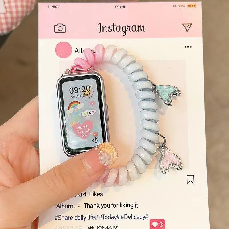 A close-up photo of a white elastic watch strap with pink accents, displayed next to a smartwatch.