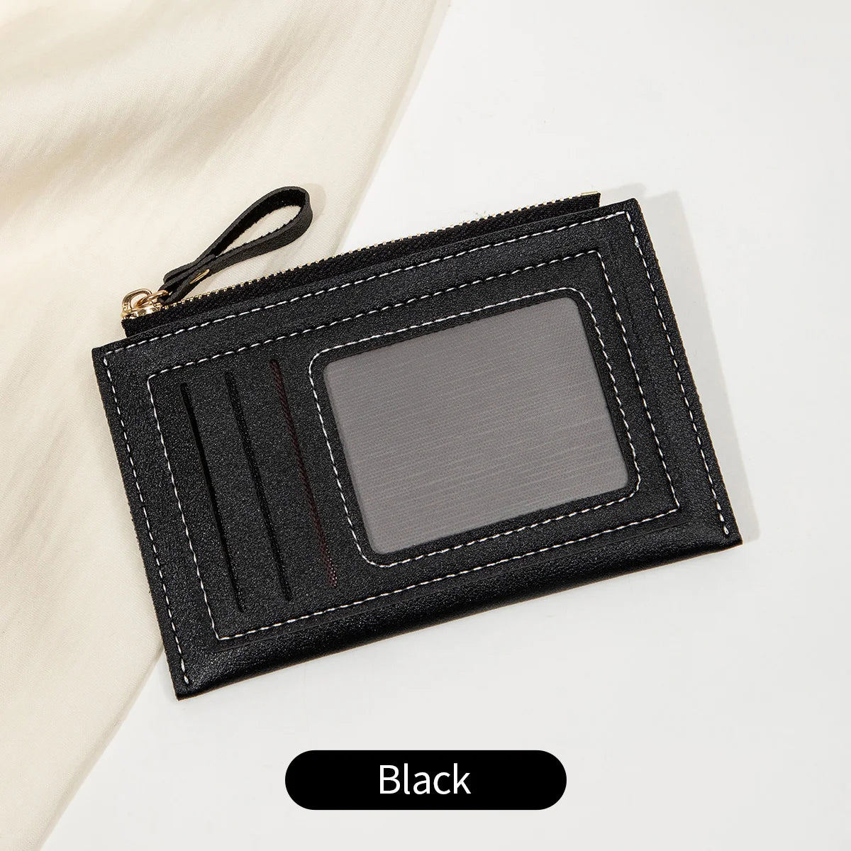 Portefeuille à pièces en cuir PU noir minimaliste avec fenêtre transparente et tirette noire, posé sur une surface blanche.