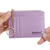 A purple leather card holder wallet with a gold chain attached, shown being held by a hand.