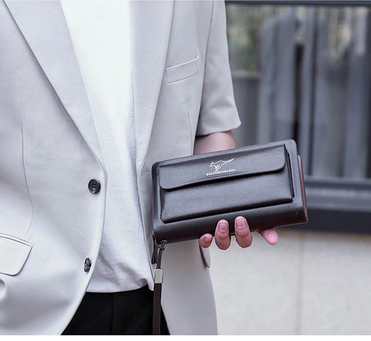 Portefeuille à fermeture éclair marron foncé pour homme, tenu par une personne en blazer gris clair.