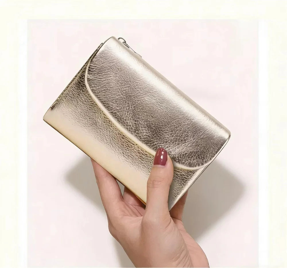 A hand holds a silver metallic leather mini card holder wallet with a textured finish.