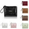A collection of mini wallets in various shades of brown, black, and green leather with gold-toned pendants.