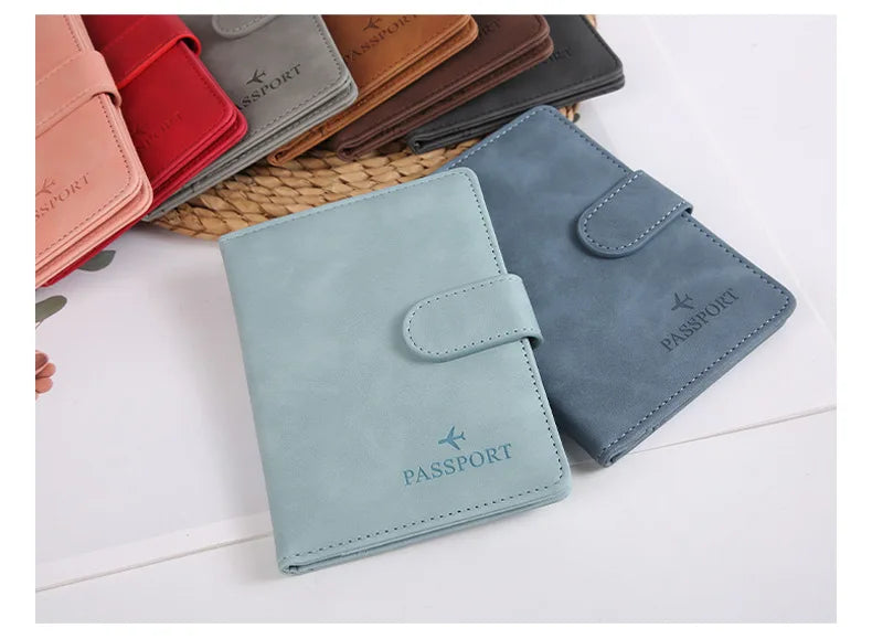 Une pile de porte-passeports et de portefeuilles en cuir bleu ardoise avec des coutures, posés sur une surface blanche.
