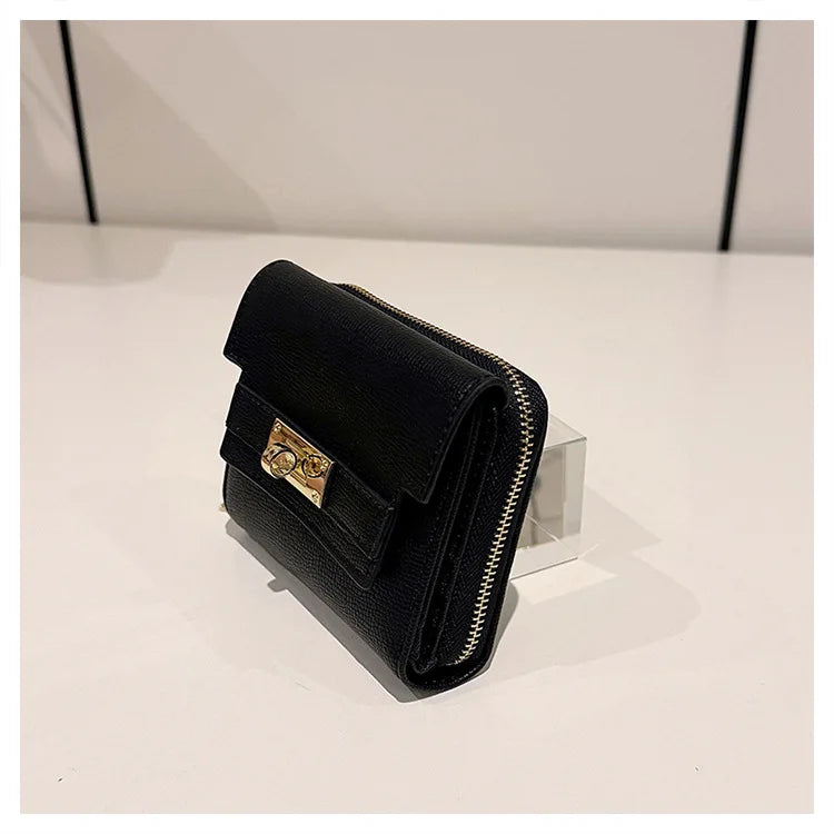 Black leather card holder with gold hardware shown on a white surface.