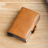 A brown leather double layer ID card holder wallet lying on a light wooden surface.