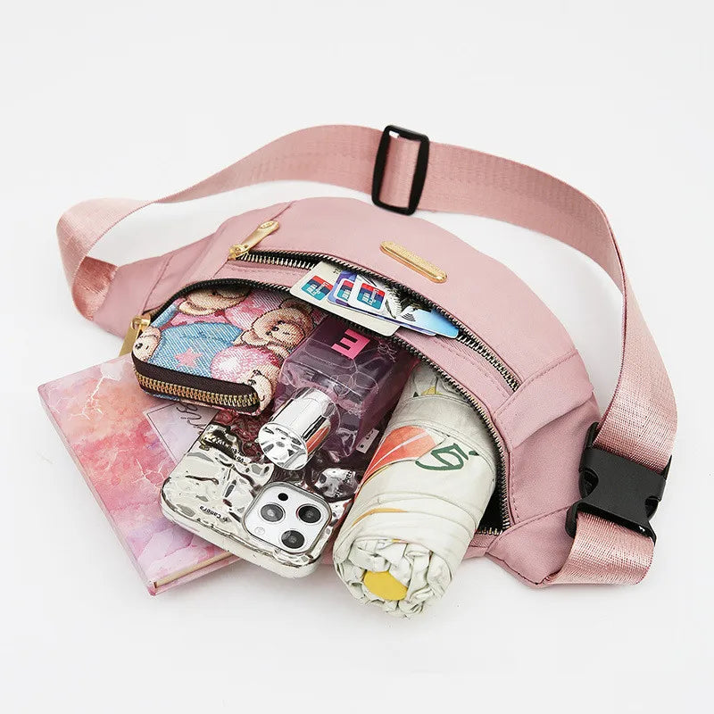 Petit sac banane imperméable rose à bandoulière avec compartiments zippés et sangle noire.