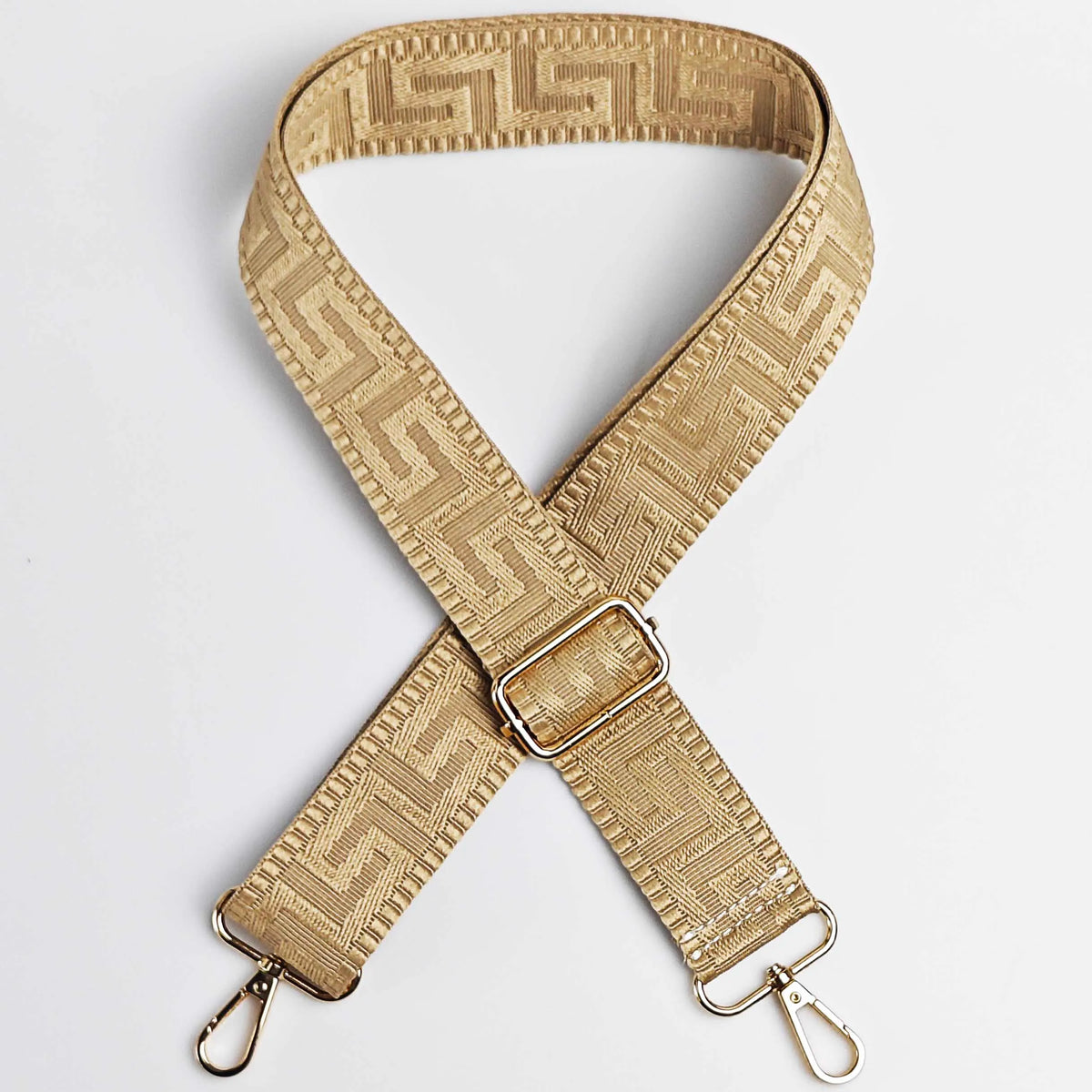 A tan woven strap with a maze pattern is shown in an X-shaped configuration.