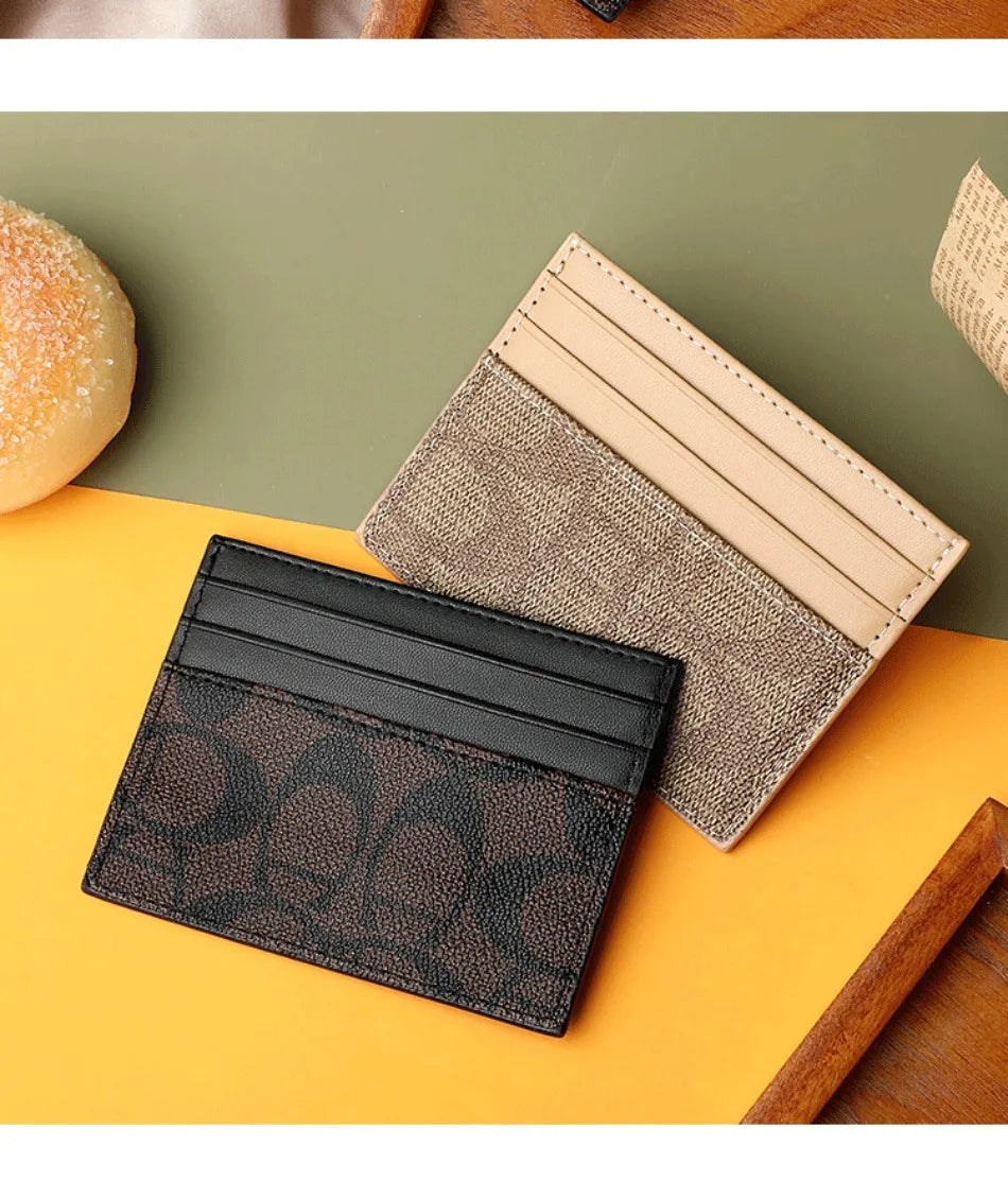 A stack of three elegant PU leather card holders in black, beige, and brown tones resting on an orange surface.