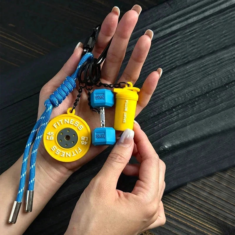 A hand holds a D-Shape nylon fitness keychain featuring yellow and blue components.