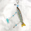 A silver acrylic keychain charm shaped like a fish with a heart loop and blue accents.