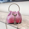 A pink crystal-embellished evening clutch with a silver chain strap resting on a light surface.